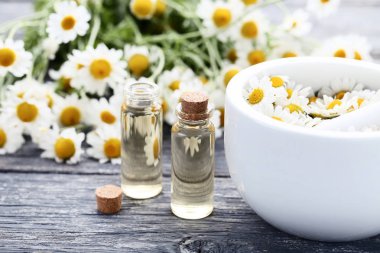 Papatya yağı harcı ve ahşap masaya çiçek şişe