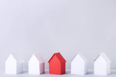 Gri arka plan üzerinde beyaz ve kırmızı kağıt evler