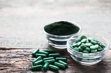 Spirulina toz ve tabletler kase gri ahşap tablo