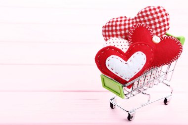 Pembe ahşap masa üzerinde kumaş yürekleri alışveriş sepeti