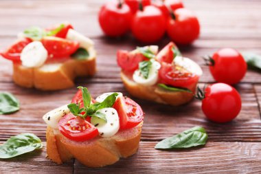 Ahşap masa Bruschettas mozzarella peyniri, domates ve fesleğen yaprakları