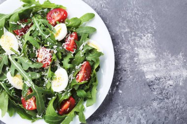 Roka salata yaprakları, domates ve gri ahşap masa üzerinde yumurta