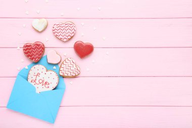 Sevgililer günü kalp şeklinde pembe ahşap masa üzerinde zarf ile tanımlama