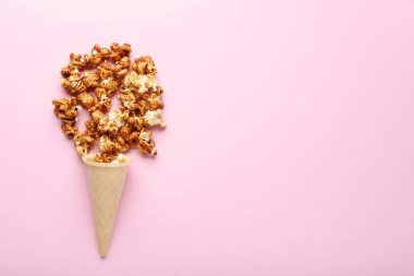 Pembe bir arka plan üzerinde gözleme koni karamelli patlamış mısır