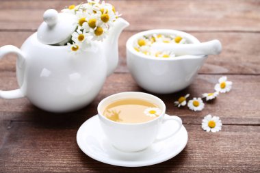 Kahverengi ahşap masa üzerinde papatya çiçeği ile çay