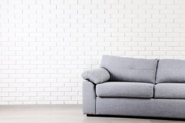 Tuğla duvar arka plan üzerinde modern gri kanepe