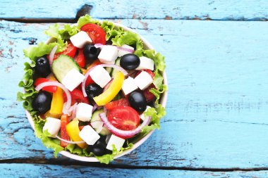 Mavi ahşap masa üzerinde kase sebze salatası