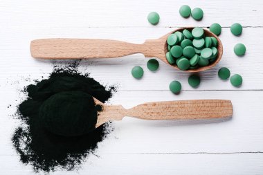 Spirulina tozu ve kaşık ahşap masa üzerinde tablet