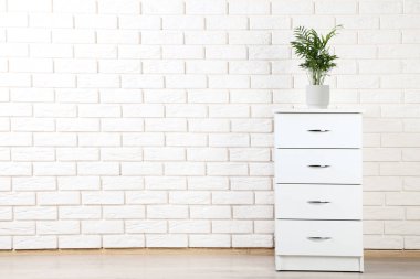 Beyaz başucundaki tuğla duvar zemin üzerine yeşil bitki ile