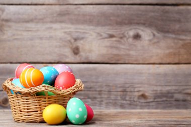 Gri ahşap masa üzerinde sepetteki renkli Paskalya yumurtaları