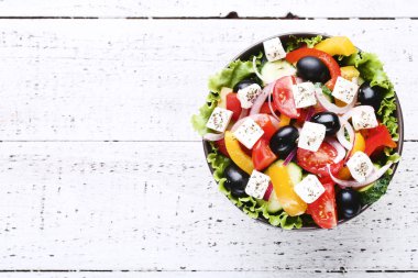 Beyaz ahşap masa üzerinde kase sebze salatası