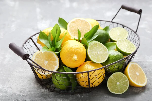 Lemons and limes with green leafs on grey wooden table