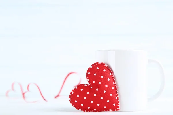 Fabric heart with cup on wooden table