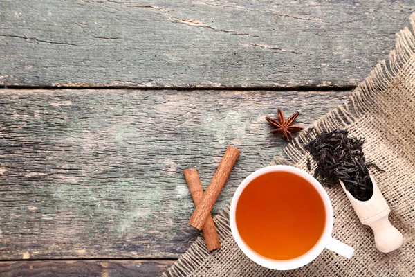 Cup of tea with cinnamon sticks on wooden table