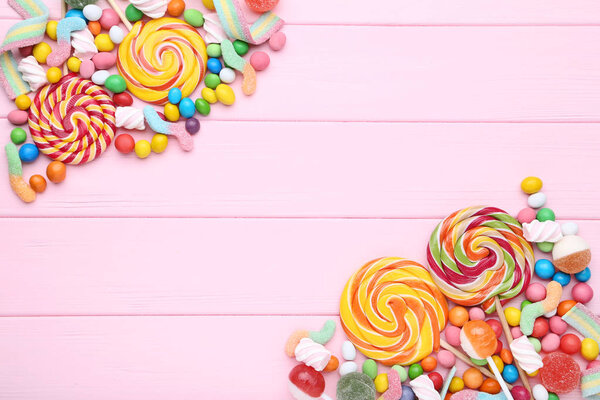 Sweet candies and lollipops on pink wooden table