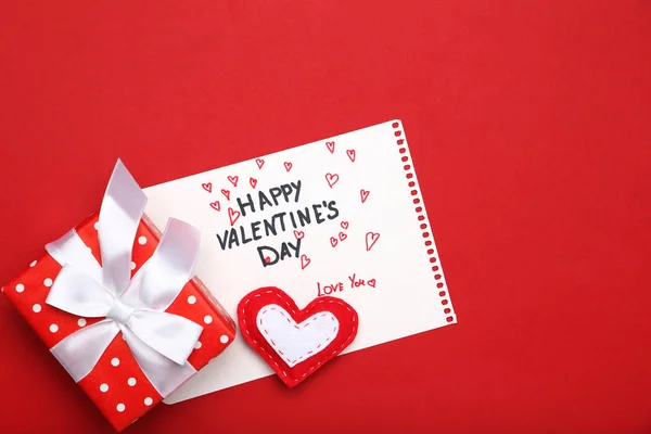 在红色背景上写一个快乐的情人节与心脏和礼品盒 — 图库照片