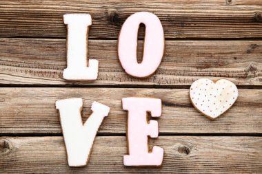 Kelime aşk kurabiye ve kalp üzerinde kahverengi ahşap masa tarafından
