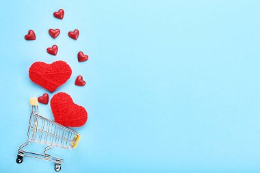 Alışveriş sepeti ile mavi arka plan üzerinde ip ve glitter kalpler