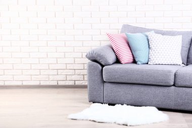 Renkli yumuşak yastık yakınındaki beyaz halı gri Divan