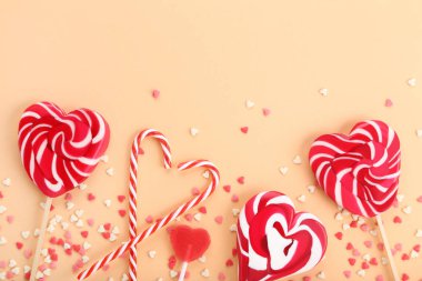 Lolipop şeker ve şeker kamışı bej renkli arka plan üzerinde kalp şeklinde