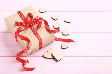 Şerit yay ve kalpleri pembe ahşap masa üzerinde hediye kutusu