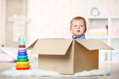Karton kutunun içinde evde oturan erkek bebek