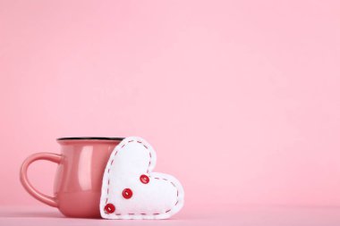 Beyaz kumaş kalp pembe bir arka plan üzerinde cup ile