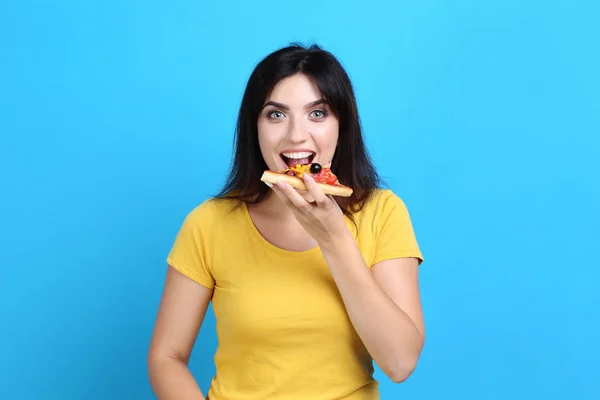 Młoda Kobieta Jedzenie Pizzy Niebieskim Tle — Zdjęcie stockowe