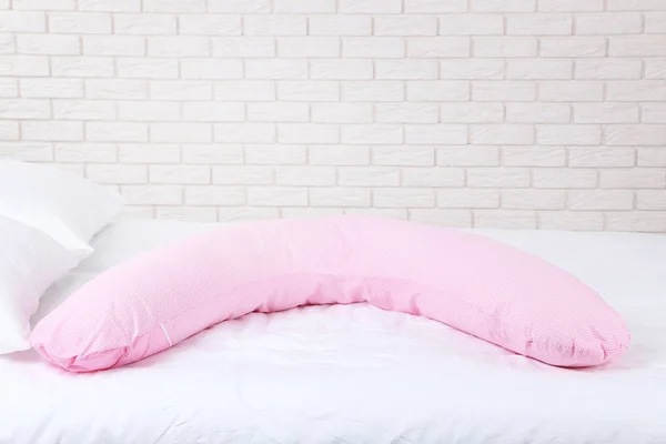 Pink body pillow on white bed