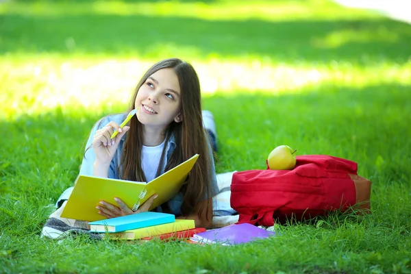 ノートや書籍の横になっているかわいい女の子公園で — ストック写真