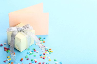 Hediye kutusu ve tebrik kartı üzerinde mavi arka plan ile sprinkles renkli kalp şeklinde