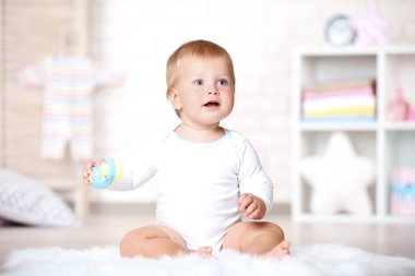 Evde halı üzerinde oturan oyuncaklarla erkek bebek
