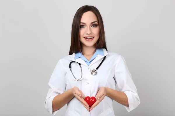Gri Arka Plan Üzerinde Stetoskop Kırmızı Kalpli Genç Doktor — Stok fotoğraf