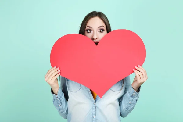 Beautiful woman holding paper heart on mint background