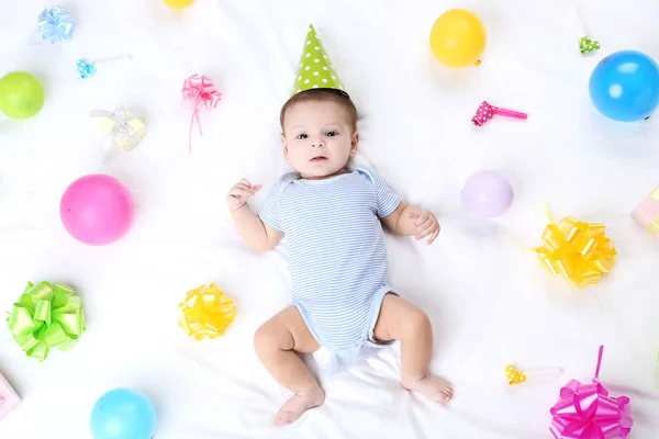 白いベッドの上に横たわる誕生日の装飾でかわいい赤ちゃん — ストック写真