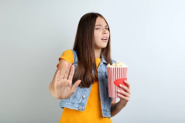 Kova gri arka plan üzerinde patlamış mısır ile tutan genç kız