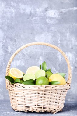 Limon ve limes yeşil yapraklar gri ahşap masa üzerinde sepeti