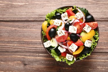 Kahverengi ahşap masa üzerinde kase sebze salatası