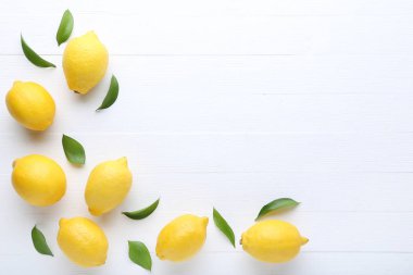 Olgun limon yeşil yapraklar üzerinde beyaz ahşap masa