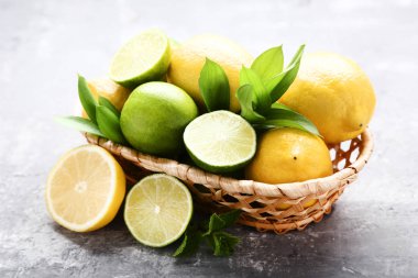 Limon ve limes yeşil yapraklar gri ahşap masa üzerinde sepeti