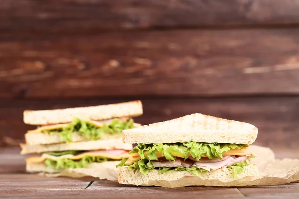 茶色の木製の背景においしいサンドイッチ — ストック写真