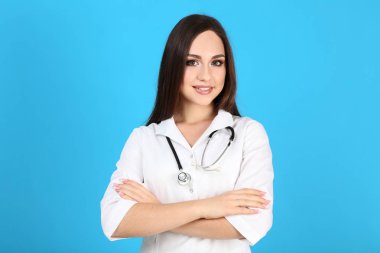 Mavi arka planda steteskobu olan genç doktorun portresi.