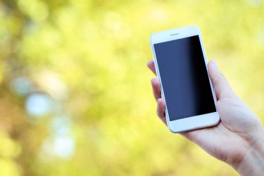 Holding ve smartphone üzerinde arka plan bulanık kullanarak kadın