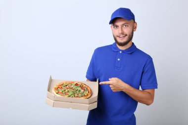 Gri arka plan üzerine karton kutu içinde pizza teslimi adam
