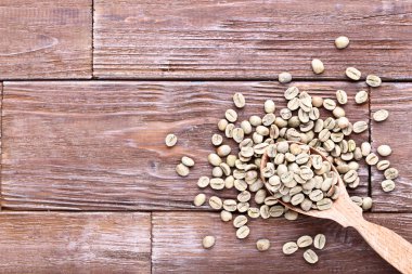 Kahverengi ahşap masa kaşık yeşil kahve çekirdekleri