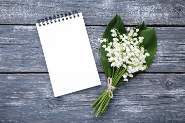 Lily vadi çiçeklerle gri ahşap masa üstünde not etmek