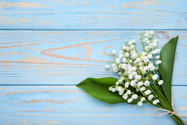 青い木製のテーブルにスズランの花 — ストック写真