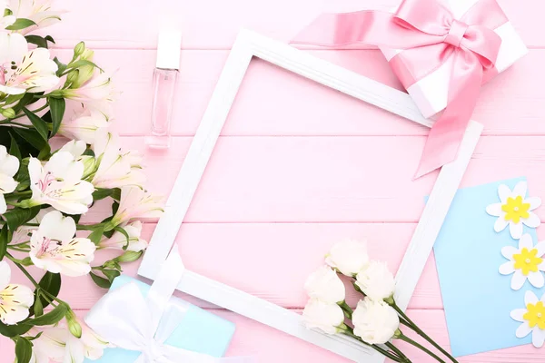 鲜花与礼品盒 香水瓶和框架在粉红色的木桌上 — 图库照片