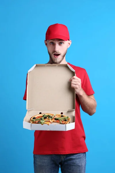 Delivery man with pizza in cardboard box on blue background