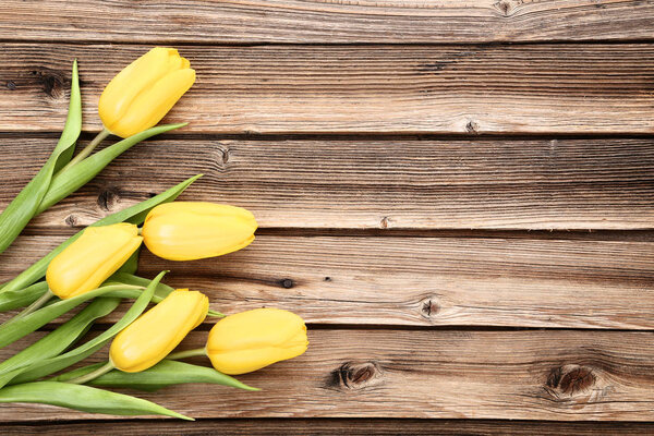 Bouquet of yellow tulips on brown wooden table